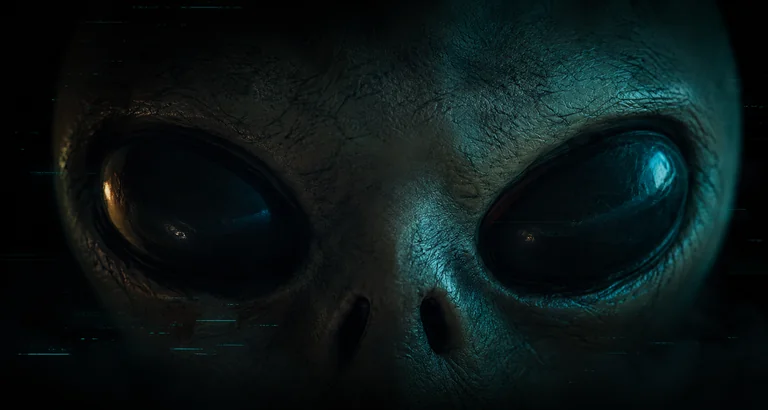 Primer plano del rostro de MANTE, el alien, iluminado con luz cian en la oscuridad